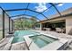 This backyard has a screened-in pool, spa, patio seating, an outdoor kitchen, and manicured landscaping at 14421 Swiss Bridge Dr, Lithia, FL 33547