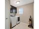 Well-lit laundry room with white tile, black cabinets and modern washer and dryer at 1949 Parterre Ave, Lutz, FL 33558
