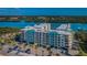 Scenic aerial view of waterfront condos with a parking lot, mature landscaping, and beautiful water views at 19531 Gulf Blvd # 604, Indian Shores, FL 33785