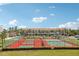 A view of the two tennis courts with palm trees lining the perimeter, condos in background, under a blue sky at 269 Madeira Cir, Tierra Verde, FL 33715