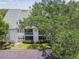 Exterior view of a well-maintained two-story condo building with manicured landscaping and a private balcony at 3261 Haviland Ct # 303, Palm Harbor, FL 34684
