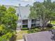 Exterior view of a well-maintained two-story condo building with manicured landscaping and a private balcony at 3261 Haviland Ct # 303, Palm Harbor, FL 34684