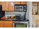 View of stainless steel oven and microwave, black cooktop and wooden cabinetry at 3261 Haviland Ct # 303, Palm Harbor, FL 34684