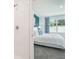 A view of the bedroom from the shower showcasing a plush bed, blue accent wall, and natural light at 32708 Winterwood Blvd, Wesley Chapel, FL 33543