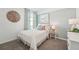 Bright bedroom with a bed with white textured comforter, matching curtains and a coastal-themed art piece at 32708 Winterwood Blvd, Wesley Chapel, FL 33543