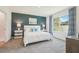 Stylish bedroom boasting a bed with a white textured comforter, bedside tables, and a large window at 32708 Winterwood Blvd, Wesley Chapel, FL 33543