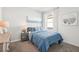Bright bedroom featuring a cozy bed with blue patterned comforter, bedside table, and beach-themed art at 32708 Winterwood Blvd, Wesley Chapel, FL 33543