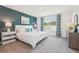 Bright bedroom with a bed featuring a white textured comforter, dresser, and a large window at 32708 Winterwood Blvd, Wesley Chapel, FL 33543