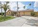 Inviting single-story home features a well-manicured lawn, long driveway and attached garage at 5616 Riddle Rd, Holiday, FL 34690