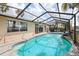 Enclosed swimming pool, next to the house, with a waterfall feature and stone border at 5616 Riddle Rd, Holiday, FL 34690
