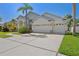 Front exterior of home with large driveway, and manicured landscaping at 7001 Cohasset Cir, Riverview, FL 33578