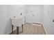Bright laundry room with utility sink, shelving, and wood-look flooring; door to the outside at 7001 Cohasset Cir, Riverview, FL 33578