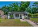 Charming home with a brick pathway, white painted brick, solar panels, and tidy landscaping at 701 W Idlewild Ave, Tampa, FL 33604