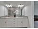 Elegant bathroom featuring dual sinks, granite countertop, decorative flower accent, and large mirror at 7417 Sungold Meadow Ct, Apollo Beach, FL 33572