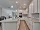 Well-lit kitchen with white cabinets, stone countertops, tile backsplash, island, and stainless appliances at 7417 Sungold Meadow Ct, Apollo Beach, FL 33572