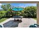 Stone patio featuring an outdoor table, chairs, shade umbrella, and lush green landscaping at 7417 Sungold Meadow Ct, Apollo Beach, FL 33572