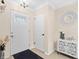 Bright foyer with a white front door, decorative mirror and cabinet, and a dark rug on wood floors at 7747 90Th N Way, Seminole, FL 33777