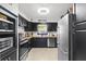 Well-lit kitchen with stainless steel appliances, light wood floors, butcher block countertops, and dark cabinets at 7747 90Th N Way, Seminole, FL 33777