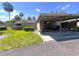 Carport view of a single Gathering home with a beige exterior, green lawn, and palm trees at 7939 Pine Dr # 7939, Temple Terrace, FL 33637