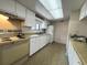 Functional kitchen featuring white cabinetry, older appliances, and a bright skylight at 7939 Pine Dr # 7939, Temple Terrace, FL 33637