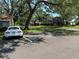 The rear of a parked car sits underneath mature trees in a parking spot at 7939 Pine Dr # 7939, Temple Terrace, FL 33637