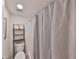 Bathroom showcasing a gray patterned shower curtain, a shelf unit, and white tiling at 880 S Village N Dr # 202, St Petersburg, FL 33716