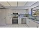 Cozy kitchen featuring stainless steel appliances, white cabinets, and a window overlooking tropical landscaping at 880 S Village N Dr # 202, St Petersburg, FL 33716
