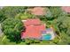 Overhead shot of a home with a red tile roof, screened pool, and manicured landscaping in a lush, green neighborhood at 8907 Magnolia Chase Cirs, Tampa, FL 33647