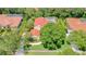 Aerial view of a residential home with a red tile roof, screened-in pool area, and mature trees at 8907 Magnolia Chase Cirs, Tampa, FL 33647