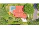 Aerial view showcasing a red tile roof, screened pool, driveway, and meticulously landscaped grounds at 8907 Magnolia Chase Cirs, Tampa, FL 33647