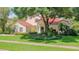 Two-story home with a red tile roof, arched entryway, well-maintained lawn, and lush landscaping at 8907 Magnolia Chase Cirs, Tampa, FL 33647
