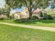 Charming home with a red tile roof, arched entryway, manicured lawn, and mature trees at 8907 Magnolia Chase Cirs, Tampa, FL 33647