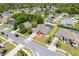 Aerial view of a gray roof home with a screened-in pool and small lawn, located on a street with mature palm trees at 1061 Archway Dr, Spring Hill, FL 34608