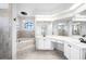 Bright bathroom with tiled floors, large mirrors, soaking tub, and white vanity at 1061 Archway Dr, Spring Hill, FL 34608