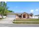 Well maintained single Gathering home with a manicured lawn, mature trees, and a neatly paved driveway to the garage at 1061 Archway Dr, Spring Hill, FL 34608