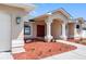 Inviting front entrance with a red double door, white columns, manicured landscaping, and decorative lighting at 1061 Archway Dr, Spring Hill, FL 34608