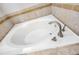 Close-up of a pristine white bathtub with brushed nickel hardware and travertine tile surround at 11207 Flora Springs Dr, Riverview, FL 33579