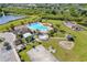 Aerial view of a bright blue community pool and playground area amidst lush greenery and surrounded by mature palm trees at 11207 Flora Springs Dr, Riverview, FL 33579