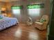 Cozy bedroom features wood flooring, nautical decor, and a sitting chair at 12501 Ulmerton Rd # 216, Largo, FL 33774