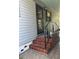 Side view of front entrance with tiled stairs, black wrought iron railings and gray vinyl siding at 12501 Ulmerton Rd # 216, Largo, FL 33774