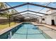 A long swimming pool, with a lounge chair, surrounded by pavers and a screen enclosure at 12641 98Th St, Largo, FL 33773