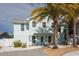 Inviting two-story light blue home with a walkway and lush palm trees in the front yard at 1411 Gray S St, Gulfport, FL 33707
