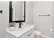 Bathroom featuring a sleek white vanity with black fixtures, a framed mirror, and a toilet with light colored flooring at 1545 Illinois Rd, Clearwater, FL 33756