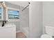 Bathroom featuring a tub/shower with marble tile, a white vanity with black fixtures, a framed window and a toilet at 1545 Illinois Rd, Clearwater, FL 33756