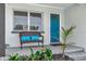 Cozy front porch featuring a charming bench, vibrant blue door, and manicured landscaping at 1545 Illinois Rd, Clearwater, FL 33756