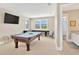 Bright game room features a pool table, shuffleboard table, a TV, and natural light at 16419 Chapman Crossing Dr, Lithia, FL 33547