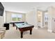Spacious game room with a pool table, shuffleboard table, and a view of lush greenery through plantation shutters at 16419 Chapman Crossing Dr, Lithia, FL 33547