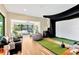Modern living room with hardwood floors, lots of natural light, and a golf simulator screen at 16419 Chapman Crossing Dr, Lithia, FL 33547