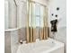Bright bathroom featuring a white bathtub with golden curtains and decorative wall accents at 16625 Goose Ribbon Pl, Wimauma, FL 33598