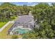 The aerial view features a screened-in pool, hot tub, and lush greenery, creating a backyard oasis at 1727 Woodpond Way, Lutz, FL 33559